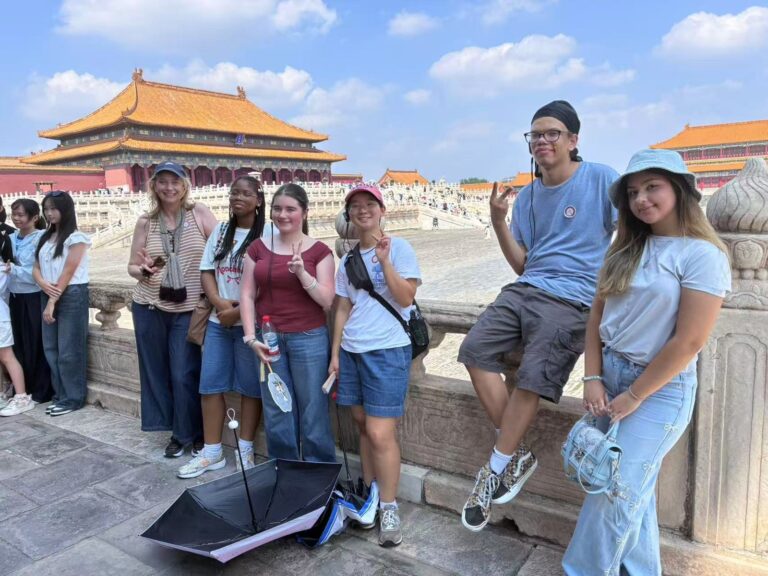 With Beijing School student companions at the Imperial Palace Six young people on a marble balustrade with red palace walls and golden roofs behind them