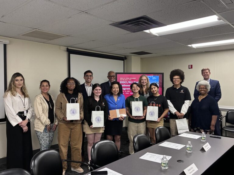 The Youth Ambassadors with Secretary of State Susan C. Lee and BXSCC members after the presentation, Annapolis, August 25, 2026 Five students holding gift bags stand with Secretary of State Susan C. Lee, who holds a wrapped gift, and BXSCC members in a conference room